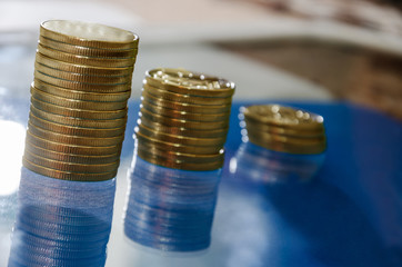 Coins are arranged in ascending order. blue background, reflecting. Close-up.