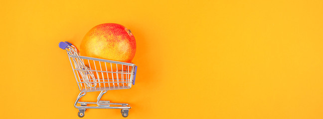 Mango fruit in shopping cart on orange background © dvoevnore
