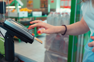 Woman pays for purchases in the store by credit card through the payment terminal