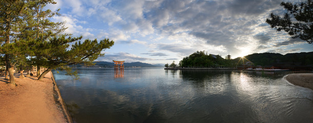 Wide panorama of sunrise near floating torii on Miyajima Island, Japan