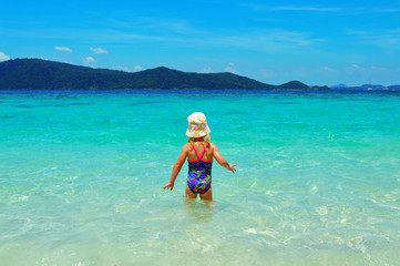 little girl in hat play on the beach alone, without a parents