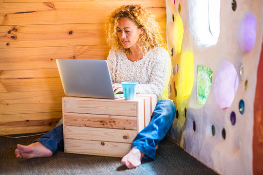 People at wotk in alternativ ehome office workstation - curly blonde pretty woman with technology computer laptop and internet connection working on the floor -