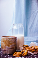 handmade ceramic cup. Coffee, pretzels and a bottle of milk on a blue textile background. Handmade tray with drops. Delicate serving. Cozy atmosphere. Handmade dishes in the interior.
