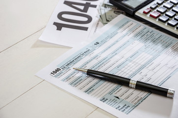 tax forms 1040 with calculator, dollars and pen