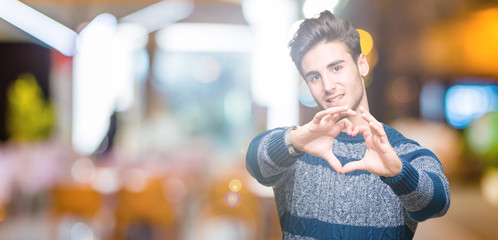 Fototapeta na wymiar Young handsome man over isolated background smiling in love showing heart symbol and shape with hands. Romantic concept.
