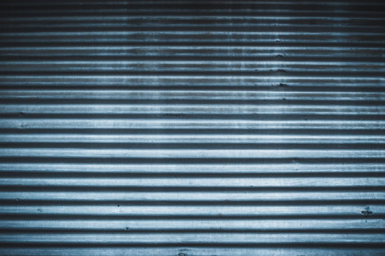 Curved metallic door with horizontal parallel stripes &ndash; Garage entrance made from hard steel with a rough surface &ndash; industry background with detailed rusty texture