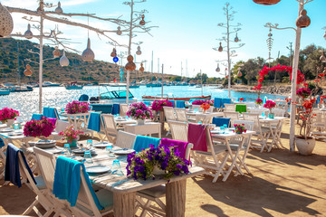 View of restaurant or cafe and bougainvillea flowers on beach in Gumusluk, Bodrum city of Turkey....