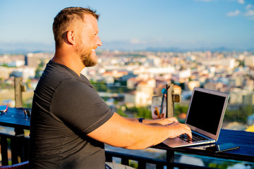 man working on a computer in a cafe with a beautiful view