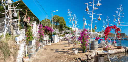 View of restaurant or cafe and bougainvillea flowers on beach in Gumusluk, Bodrum city of Turkey....