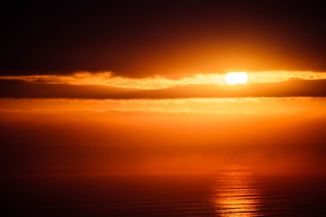 The rising over the ocean with dramatic clouds as viewed from an elevated vantage point.