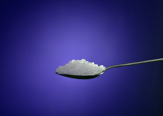 sugar crystal on spoon isolated on blue background