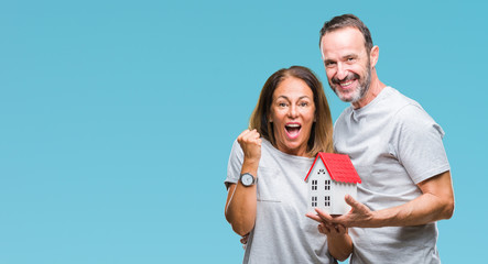 Middle age hispanic casual couple buying new house over isolated background screaming proud and...