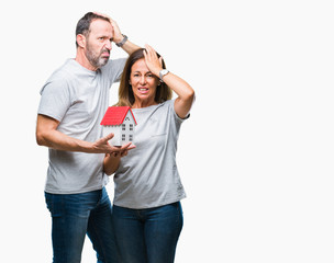Middle age hispanic casual couple buying new house over isolated background stressed with hand on...