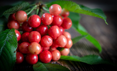 Cherry fresh red berries, and green leaves on a wooden background