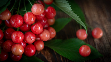 Cherry fresh red berries, and green leaves on a wooden background