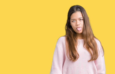 Young beautiful brunette woman wearing pink winter sweater over isolated background sticking tongue out happy with funny expression. Emotion concept.