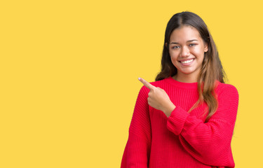 Young beautiful brunette woman wearing red winter sweater over isolated background cheerful with a smile of face pointing with hand and finger up to the side with happy and natural expression on face