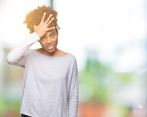 Beautiful young african american woman over isolated background surprised with hand on head for...