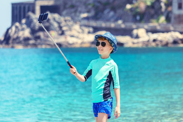 Little fashion influencer taking selfie on beach for social media