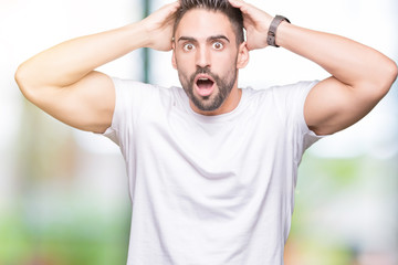 Handsome man wearing white t-shirt over outdoors background Crazy and scared with hands on head, afraid and surprised of shock with open mouth