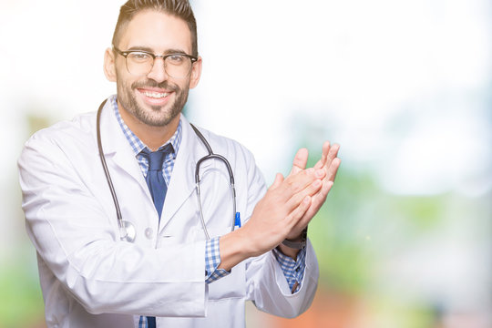 Handsome young doctor man over isolated background Clapping and applauding happy and joyful, smiling proud hands together
