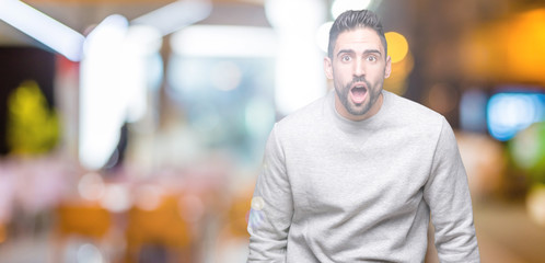 Fototapeta na wymiar Young handsome man wearing sweatshirt over isolated background afraid and shocked with surprise expression, fear and excited face.
