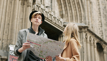 Two stylish friend standing at the street and look for something using a map