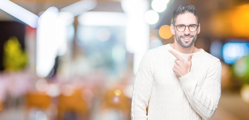 Fototapeta na wymiar Young handsome man wearing glasses over isolated background cheerful with a smile of face pointing with hand and finger up to the side with happy and natural expression on face
