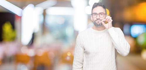 Young handsome man wearing glasses over isolated background mouth and lips shut as zip with...