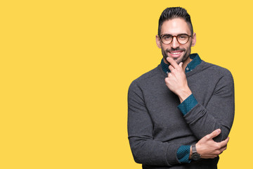 Young handsome man wearing glasses over isolated background looking confident at the camera with smile with crossed arms and hand raised on chin. Thinking positive.