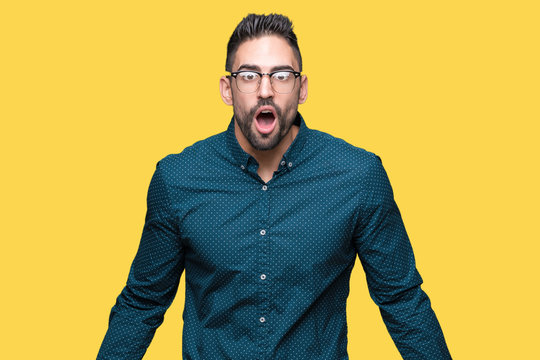 Young handsome business man wearing glasses over isolated background afraid and shocked with surprise expression, fear and excited face.