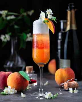 Layered bellini cocktail with peaches on dark background