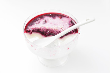 Half eaten jelly  in a glass vase with a white spoon