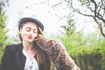 Frühling: elegante junge Frau mit Hut, 20 - 30 Jahre alt, genießt mit Ihrem Hund den Sonnenschein...