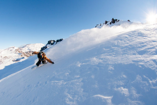 A women snowboards powder on a sunny bluebird day in Argentina.
