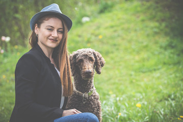 Frühling: elegante junge Frau mit Hut, 20 - 30 Jahre alt, genießt mit Ihrem Hund den Sonnenschein...