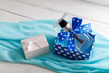 Obraz na płótnie Canvas Bottle of woman perfume on aqua background with white gift box. Blue packeging of present.