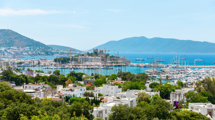 Fototapeta na wymiar Panoramic View of Aegean sea, traditional white houses marina and Bodrum Castle in Bodrum city of Turkey. Aegean style colorful street, wall, house and flowers in Bodrum town Turkey.