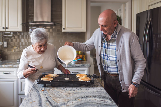 Great grandma cooking pancakes with her adult son