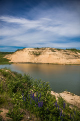 Fototapeta na wymiar Blue sky and lake in the sand quarry with green grass