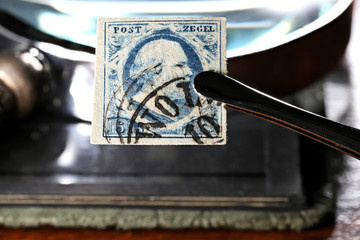 5c stamp of the Netherlands from the series first issued in 1852 held by tweezers. It is the first...