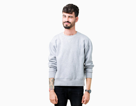 Young handsome man wearing sweatshirt over isolated background winking looking at the camera with sexy expression, cheerful and happy face.