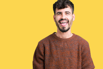 Fototapeta premium Young handsome man wearing winter sweater over isolated background sticking tongue out happy with funny expression. Emotion concept.