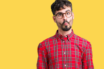 Young handsome man wearing glasses over isolated background making fish face with lips, crazy and comical gesture. Funny expression.