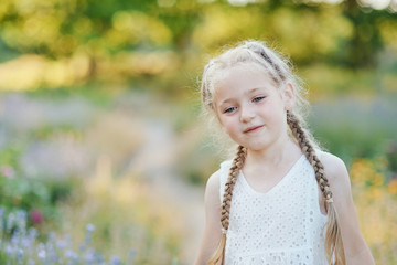 Naklejka premium Little girl in lavender field. kids fantasy. Smiling girl sniffing flowers in summer purple lavender field.