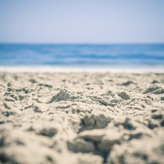 Sand in Focus in Foreground, Ocean Blurred Beyond