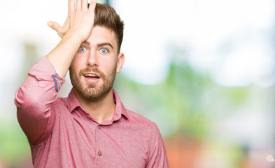 Young handsome business casual man surprised with hand on head for mistake, remember error. Forgot,...