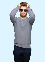 Fototapeta premium Young handsome man wearing sunglasses suffering from headache desperate and stressed because pain and migraine. Hands on head.