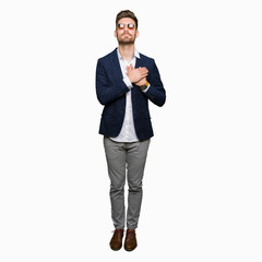 Young handsome elegant man wearing sunglasses and fashion blazer smiling with hands on chest with closed eyes and grateful gesture on face. Health concept.