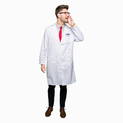 Young handsome scientist man wearing glasses shouting and screaming loud to side with hand on mouth. Communication concept.